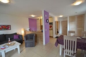 A living room with a sofa, a coffee table, and a dining table with chairs. There is a kitchen area with cabinets and a microwave. - Just 500 meters from the sandy Baltic Sea beach, Wi-Fi, and a washing machine with a covered patio (Glowe)