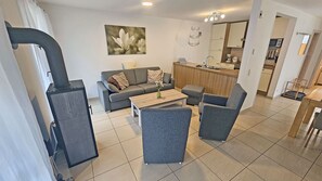 A modern living room with a sofa, armchairs, a coffee table, and a kitchen area in the background. - Just 400 meters from the sandy Baltic Sea beach, Wi-Fi, and a washing machine with a covered patio (Glowe)