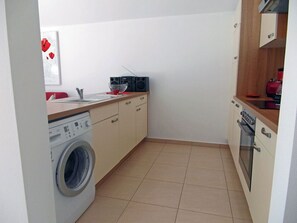 A compact kitchen with a washing machine, a microwave, and a stove. - Just 500 meters from the sandy Baltic Sea beach, Wi-Fi, and a washing machine with a covered balcony (Glowe)
