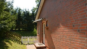 Een bakstenen gebouw met een witte hekken en een pad dat naar een deur leidt.