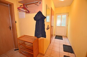 A hallway with a wooden bench, a coat rack, and a door. - Just 700 meters from the sandy Baltic Sea beach, Wi-Fi and a dishwasher, patio with patio furniture (Glowe)