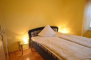 A single bed with a headboard, a bedside table with a lamp, and a window with curtains. - Just 700 meters from the sandy Baltic Sea beach, Wi-Fi and a dishwasher, patio with patio furniture (Glowe)