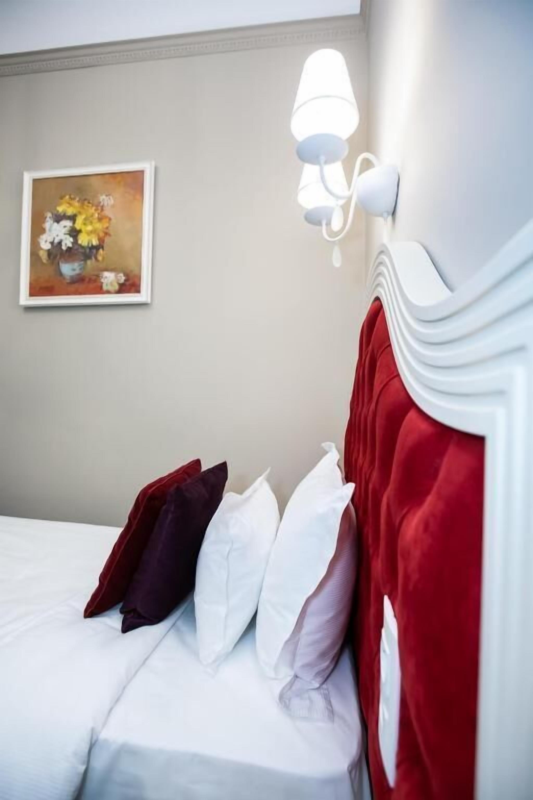Une chambre d’hôtel avec un lit, des oreillers, un luminaire fixé au mur et un tableau accroché au mur.