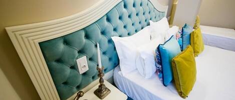 A hotel room with a tufted headboard, a bedside table with a lamp, and a bed with multiple pillows.