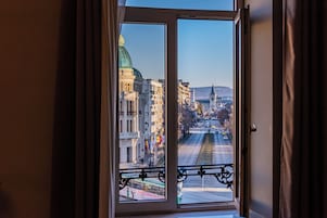 A window with a view of a cityscape, including buildings and a bridge.