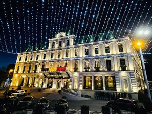 Un edificio histórico con una entrada imponente, múltiples ventanas y una fachada bien iluminada.