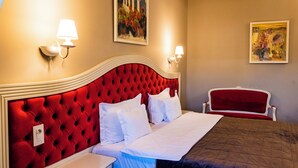 A hotel room with a red tufted headboard, white bedding, a bedside table, and two wall-mounted lamps. - Grand Hotel Traian (Iași)
