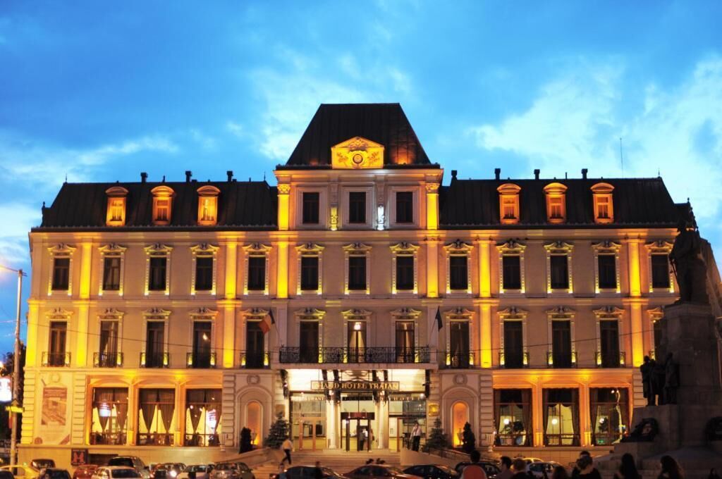 A historic hotel building with classical architecture, a prominent entrance, and a statue in front.