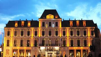 A historic hotel building with classical architecture, a prominent entrance, and a statue in front.