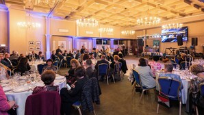 A formal event with attendees seated at round tables, a stage with a large screen, and chandeliers. - Grand Hotel Traian (Iași)