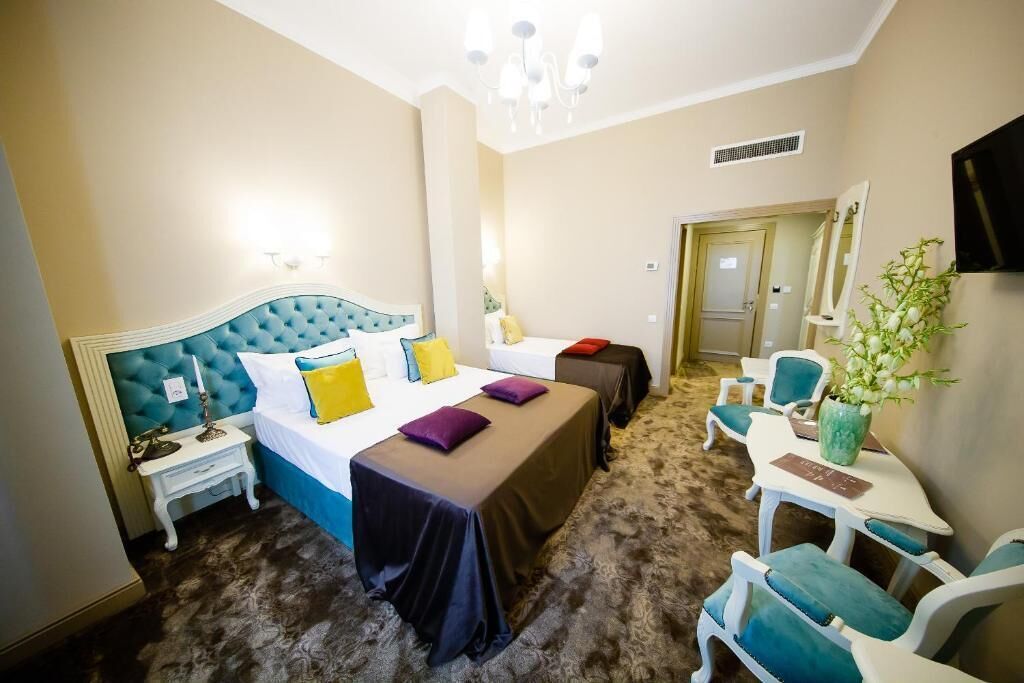 Una camera d'albergo con un letto grande, un comodino, una sedia, un tavolino e una pianta.