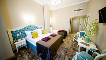 Una camera d'albergo con un letto grande, un comodino, una sedia, un tavolino e una pianta.