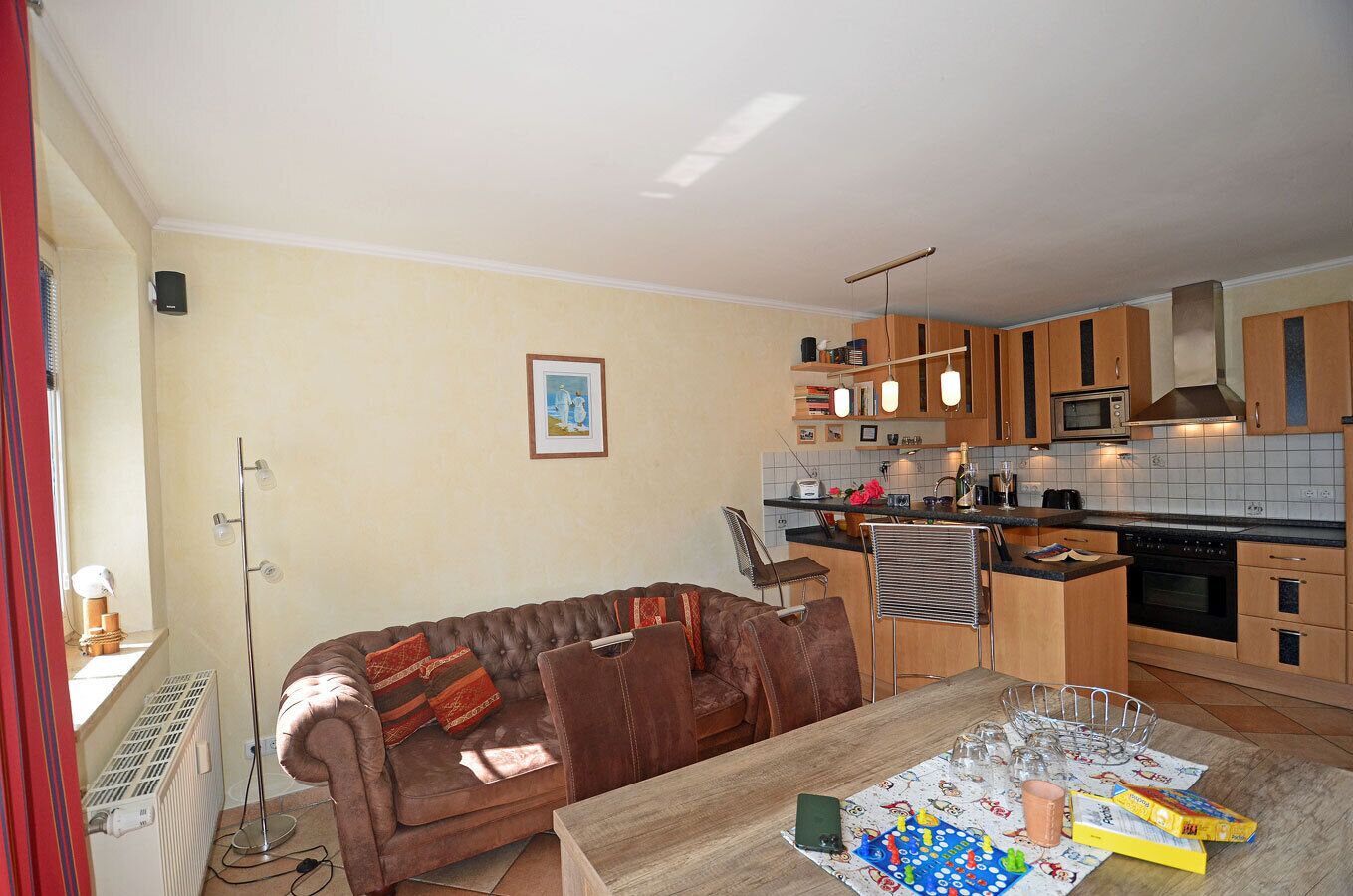Una cocina moderna con comedor, un sofá de cuero marrón y una mesa con juegos de mesa.