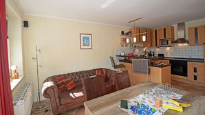 A modern kitchen with a dining area, a brown leather sofa, and a table with board games. - About 50 meters to the sandy beach and the boardwalk, Wi-Fi, washing machine, about 300 meters to the harbor (Glowe)