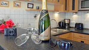 A bottle of champagne, glasses, a camera, and sunglasses on a kitchen counter. - About 50 meters to the sandy beach and the boardwalk, Wi-Fi, washing machine, about 300 meters to the harbor (Glowe)