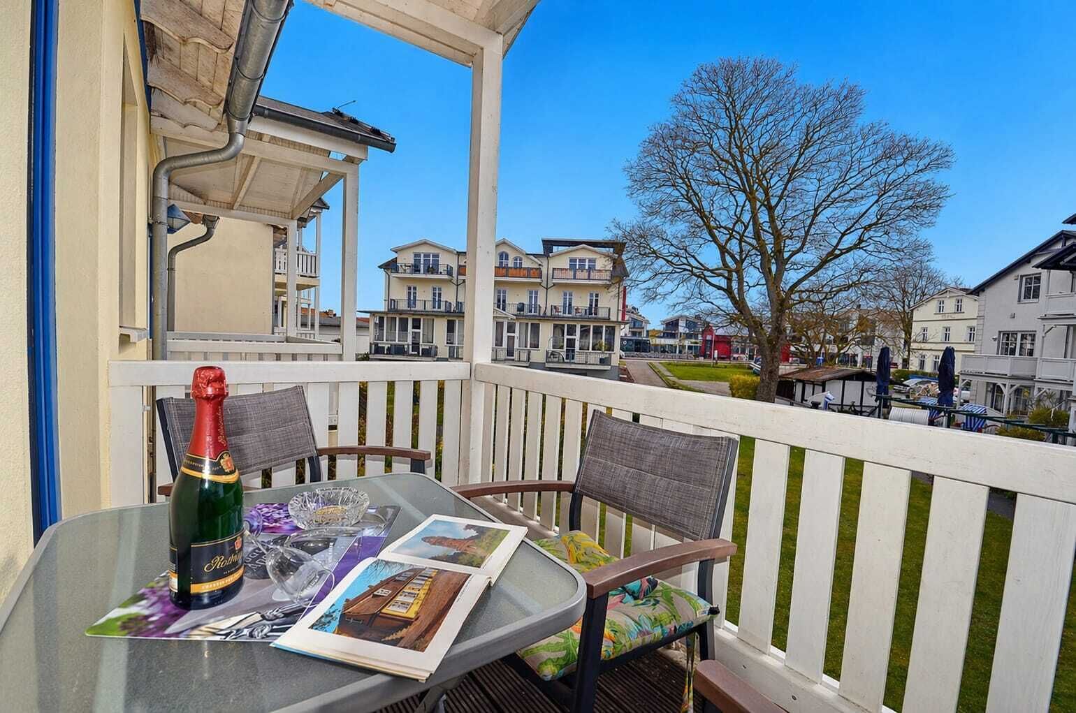 A balcony with a table, chairs, a bottle of champagne, and a magazine.