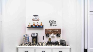 A coffee station with a coffee machine, cups, and a sign that says 'Coffee and Tea.' - Gettin' Woodsy and Cutesy by Lake Travis (Lago Vista)