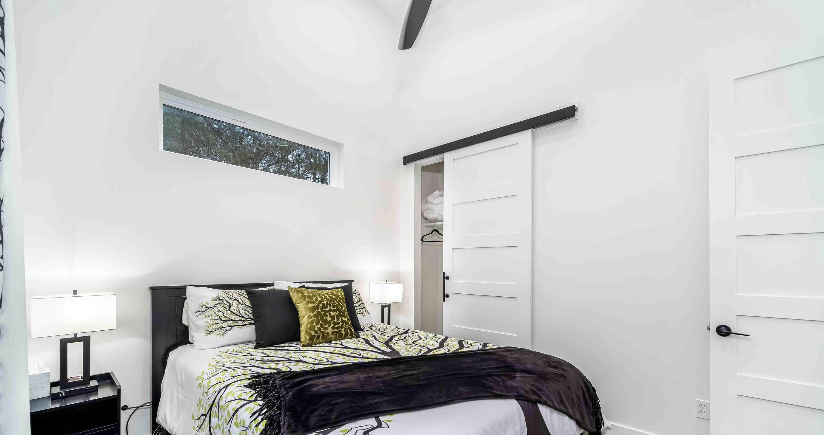 A bedroom with a bed, bedside tables, a wardrobe, and a window with a view of trees.