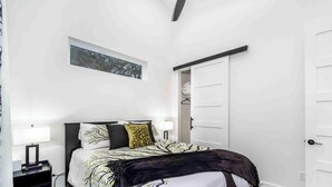 A bedroom with a bed, bedside tables, a wardrobe, and a window with a view of trees. - Gettin' Woodsy and Cutesy by Lake Travis (Lago Vista)