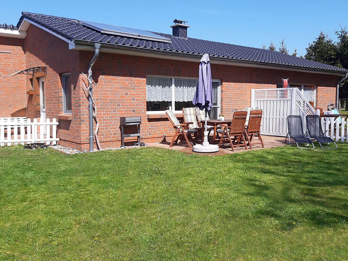 A brick house with a patio area, outdoor furniture, and a white picket fence.