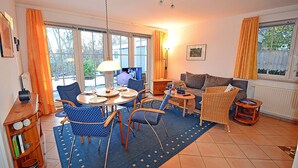 Een woonkamer met een eethoek, een bank en een televisie.