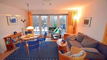 A cozy living room with a sofa, chairs, a dining table, and a television.