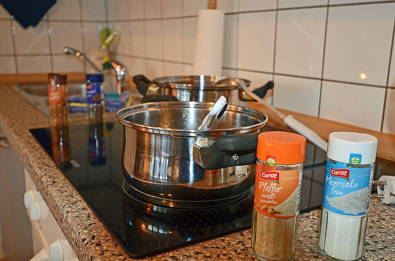 A kitchen with a stove, pots, and spices.