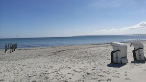 Een strand met witte rieten stoelen en een vlaggenmast.