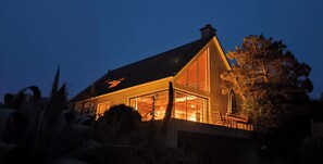 A house with a large window, a balcony, and a chimney.