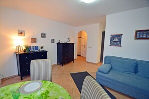 A living room with a sofa, a dining table with a plate and glass, a dresser, and a wall with framed pictures. - Ground-floor apartment with a terrace in the Breege residential complex, 900 m from the beach, Internet (Breege)