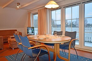 A dining area with a round table, chairs, and a television. - 1st floor with balcony, 900 meters from the Baltic Sea beach, Internet/Wi-Fi (Breege)