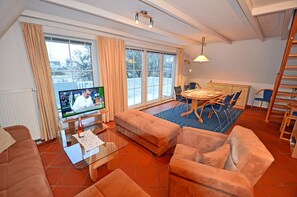 A living room with a television, sofa, dining table, and chairs. - 1st floor with balcony, 900 meters from the Baltic Sea beach, Internet/Wi-Fi (Breege)