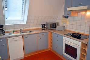 A compact kitchen with a dishwasher, microwave, toaster, and stove. - 1st floor with balcony, 900 meters from the Baltic Sea beach, Internet/Wi-Fi (Breege)