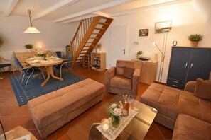 Ein gemütliches Wohnzimmer mit einer Sofagarnitur, einem Esstisch und einer Treppe.