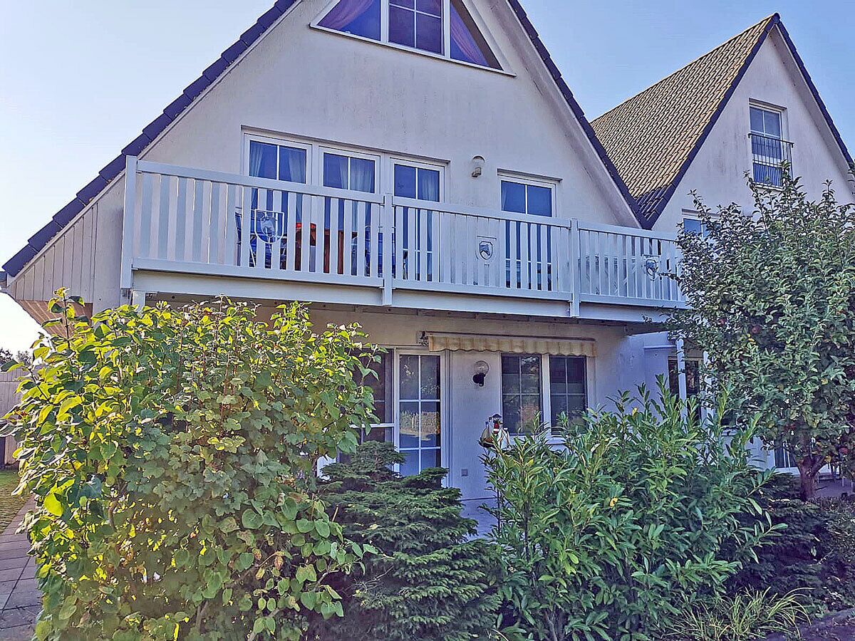 A two-story house with a balcony, a front door, and a small porch area.
