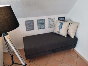 A dark-colored sofa with two pillows, a lamp, and three wall-mounted signs with text. - Only 900 meters from the beach, 1st floor with balcony, Internet/Wi-Fi, washing machine (Breege)