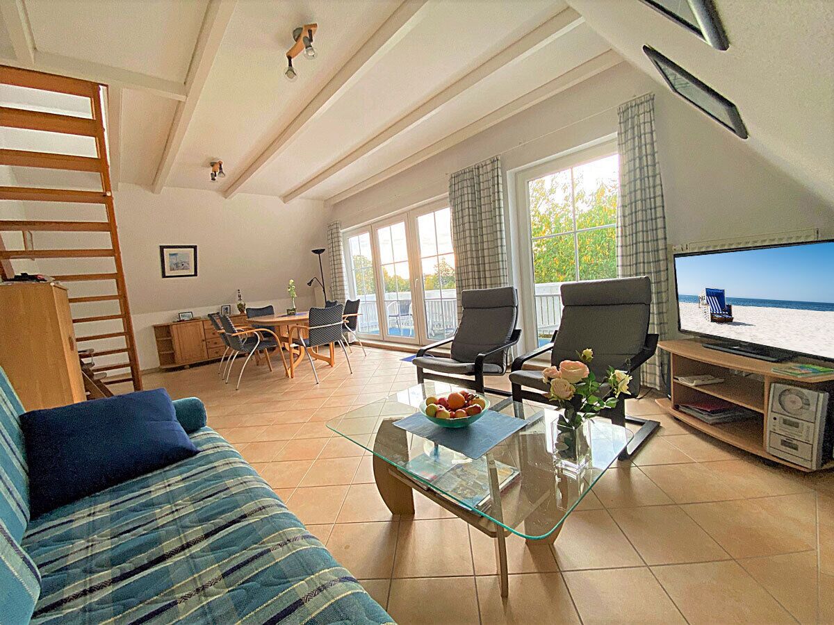 Ein Wohnzimmer mit einer Couch, einem Couchtisch, einem Fernseher und einem Balkon mit Blick.