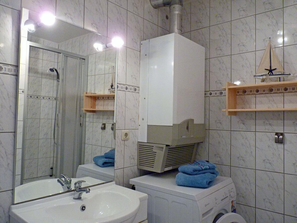 Ein Badezimmer mit Waschbecken, Spiegel, Dusche und einem weißen Heizgerät.