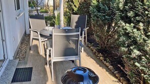 Une terrasse extérieure équipée d’un barbecue, de chaises et d’une table.