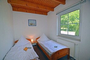 A room with two single beds, a wooden ceiling, a window with a view of greenery, and a framed picture on the wall. - Only 900 meters from the beach; ground floor with a terrace, sauna, and internet/Wi-Fi available (Breege)