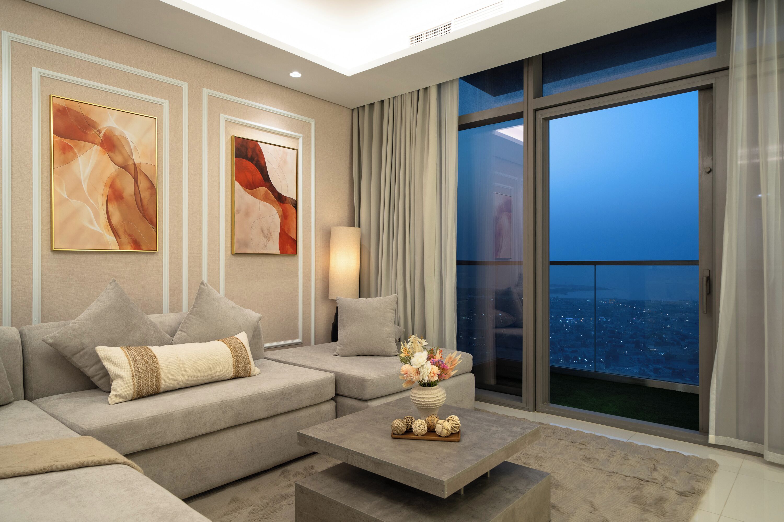 A modern living room with a sofa, a coffee table, and two abstract paintings.