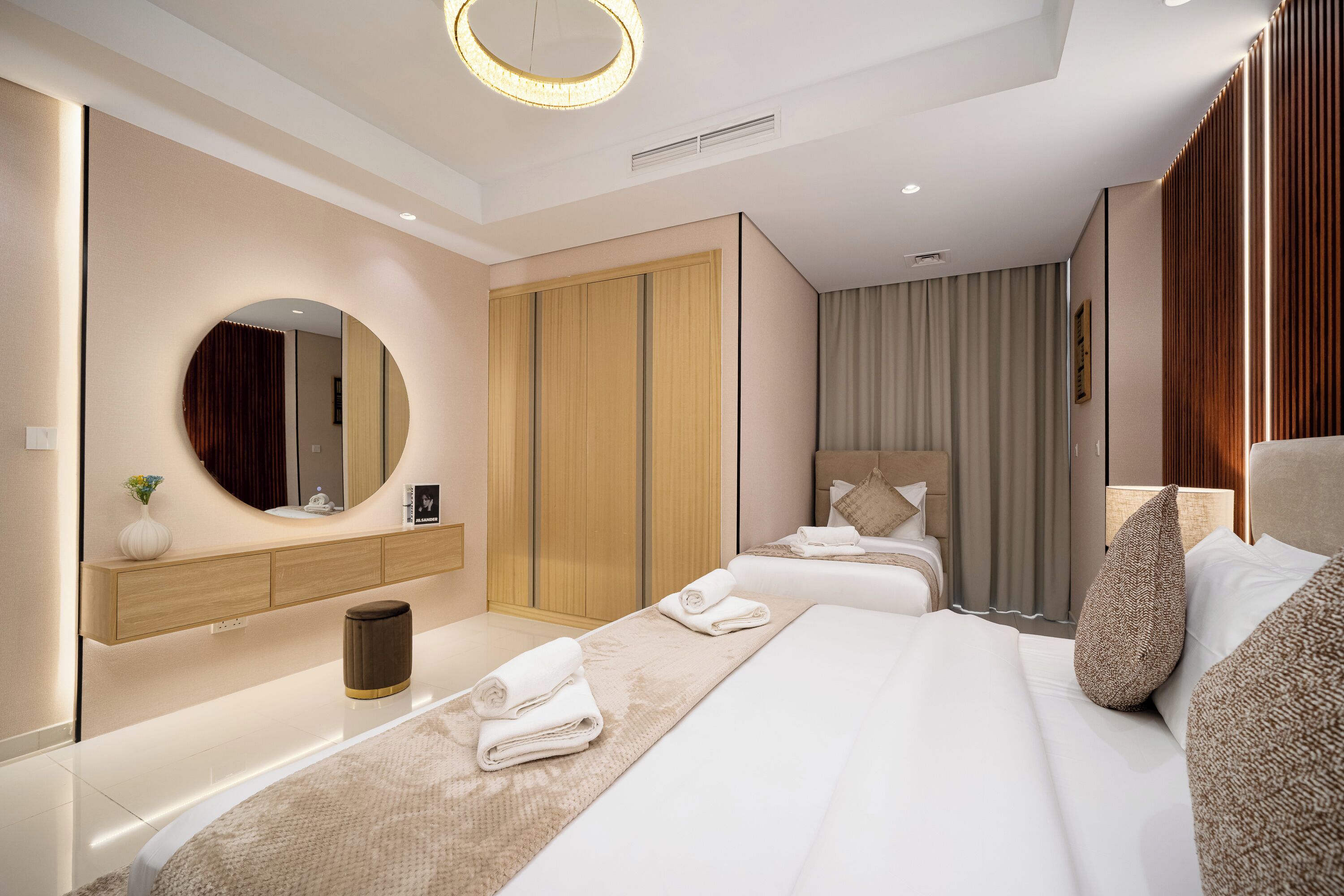 Una habitación de hotel moderna con una cama grande, una mesita de noche, un espejo, un armario y un espacio para el baño.