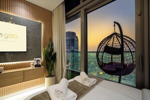 A hotel room with a bed, a hanging chair, a view of the city, and a reception desk. - Gogoto10 Luxury 2BR Paramount 64F Infinity Pool (Dubai)