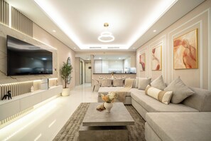 A modern living room with a flat-screen TV, a sofa, a coffee table, and artwork on the walls. - Gogoto10 Luxury 2BR Paramount 64F Infinity Pool (Dubai)