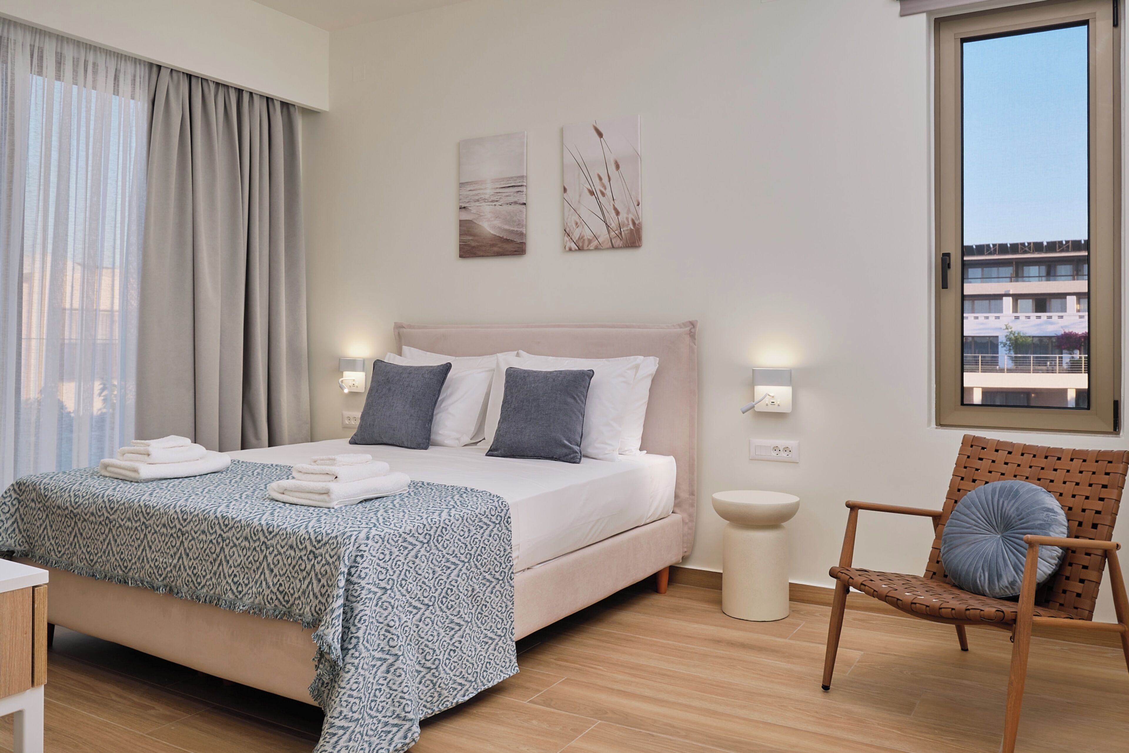 Une chambre d’hôtel avec un lit, une chaise, une table de chevet et une fenêtre.