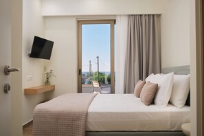 Ein Hotelzimmer mit Bett, Wand-Fernseher, Fenster mit Blick ins Freie und Tür.