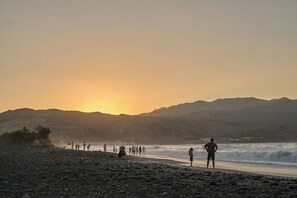 A beach with people and waves at sunset. - Votsalo Seaside Villa (Kamisiana)