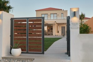 En lukket indgang til en moderne villa med en tydelig sti til bygningen.