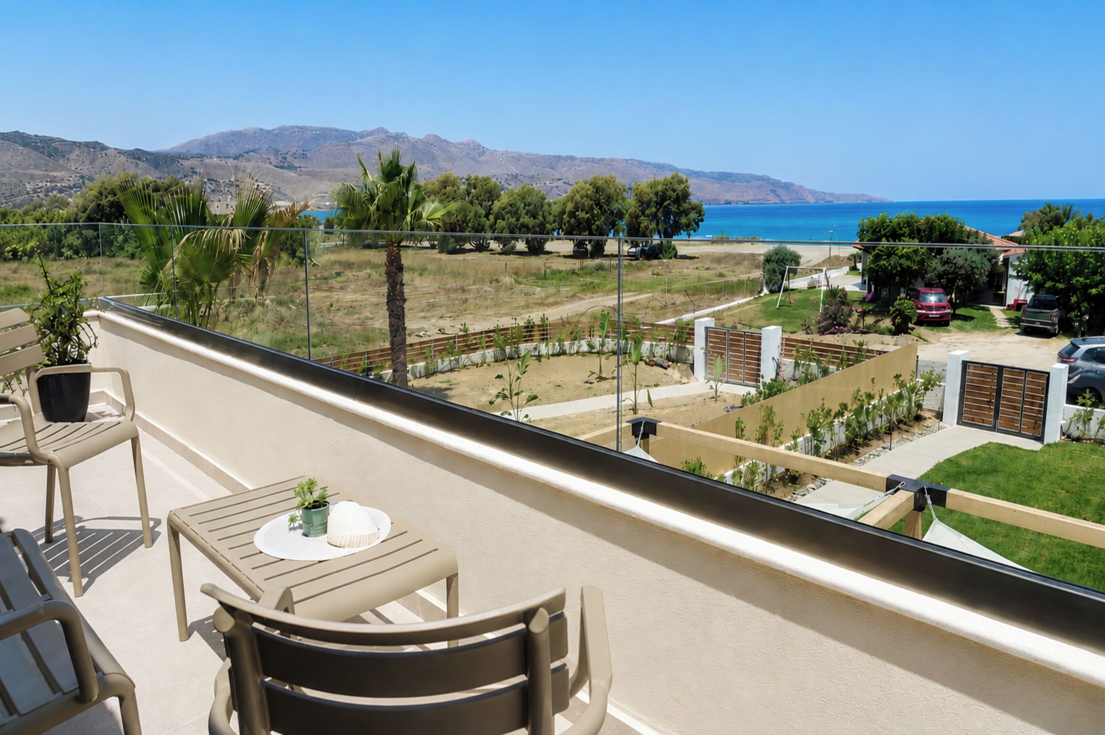 A balcony with a view of a coastal landscape, including mountains and a beach.