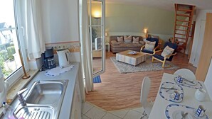 Un espai habitable compacte amb cuina americana, zona de dinar i seients.